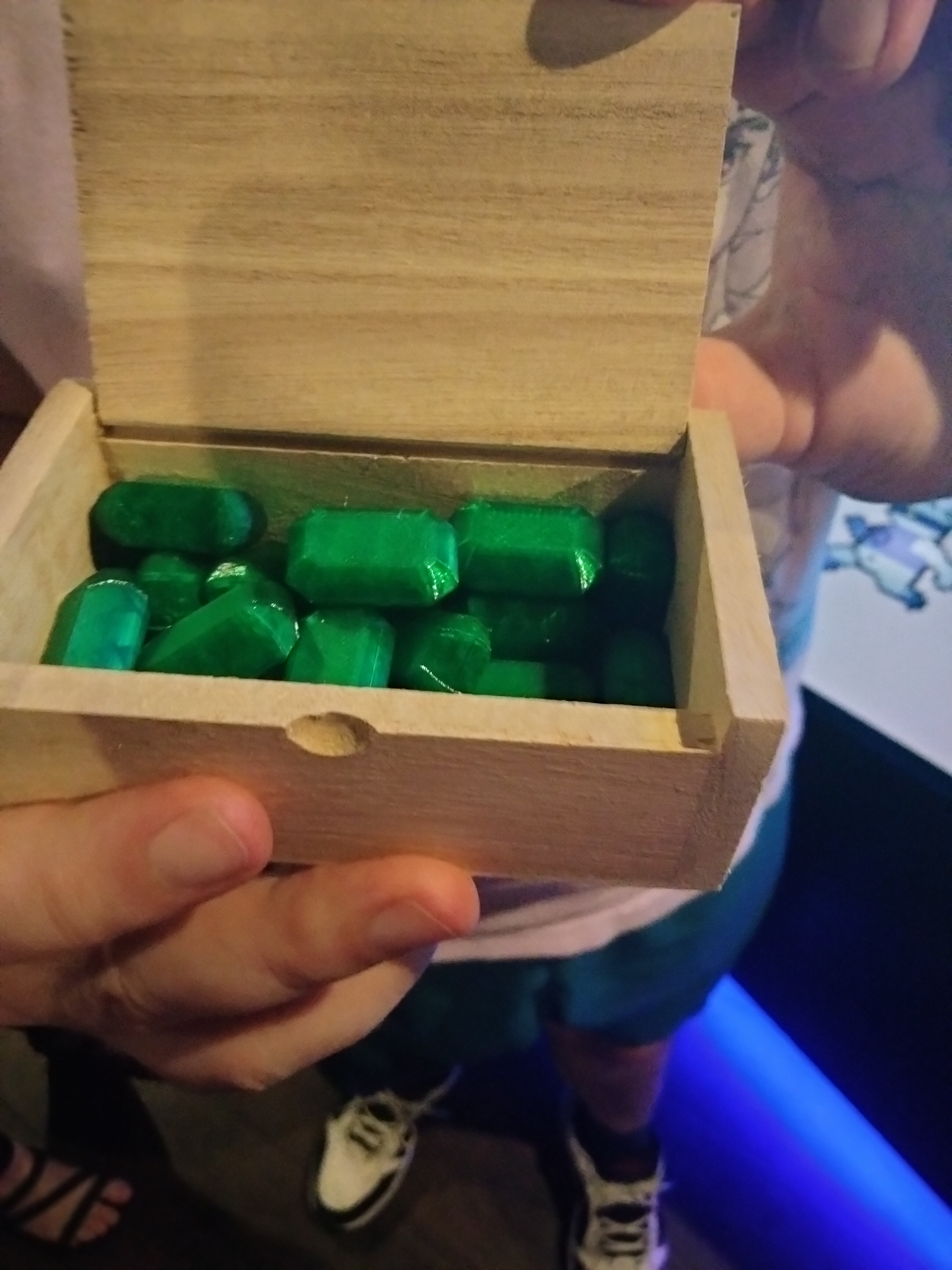A small wooden box, containing many 3D-printed green emeralds.