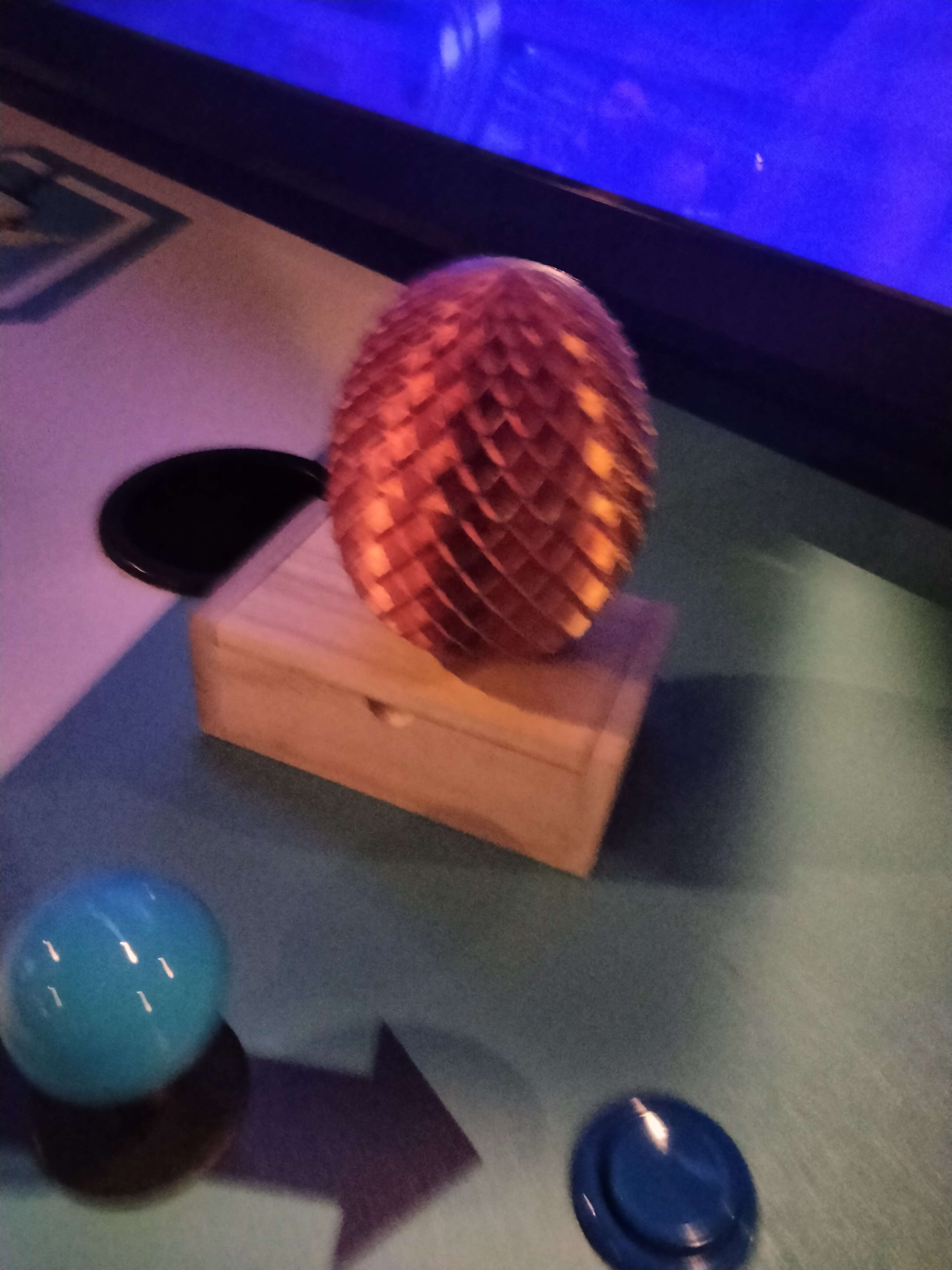 A pineapple-like object with an unscrewable top, placed atop a small wooden box.